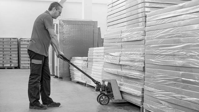 Employee working with a standard hand pallet truck in a warehouse